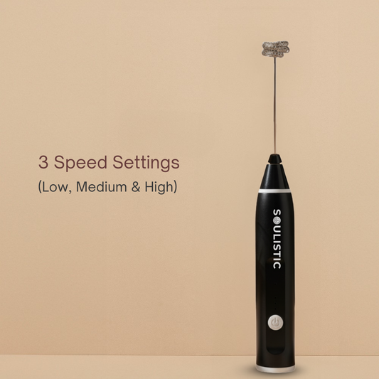Black handheld milk frother with 'Soulistic' branding on a beige background