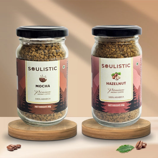 Two jars of Soulistic Mocha and Soulistic Hazelnut coffee on a wooden stand with a beige background