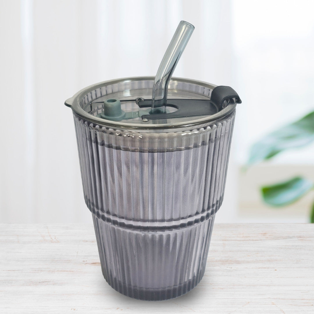 Soulistic ribbed glass sipper with a lid and straw on a light marble surface