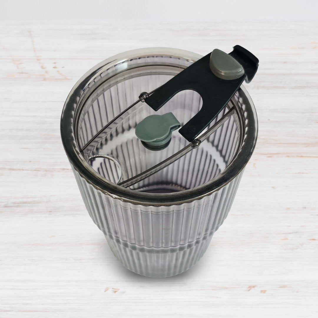 Soulistic ribbed glass sipper with open lid on a light marble surface
