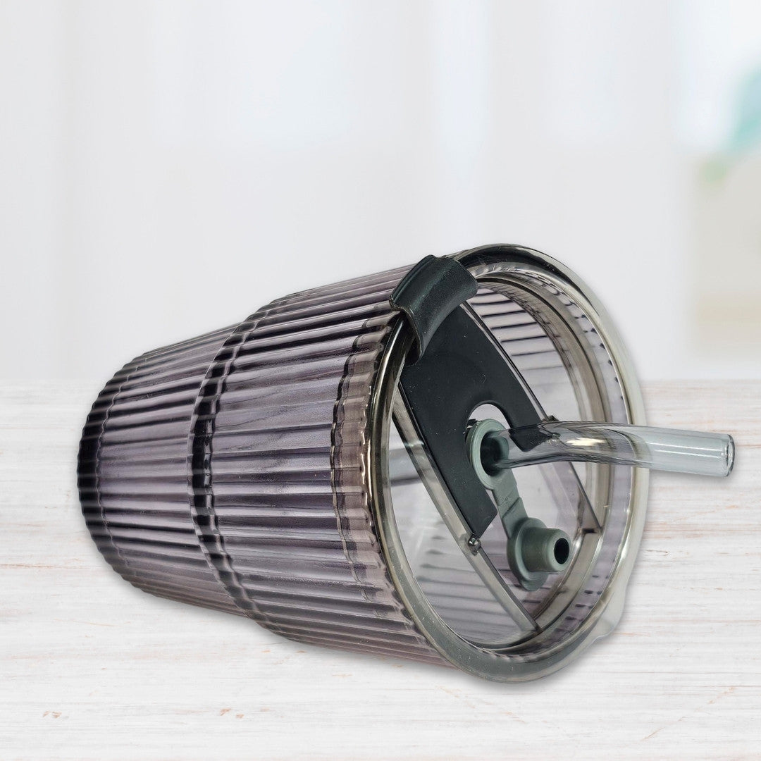 Soulistic ribbed glass sipper with a lid and straw lying on a light marble surface